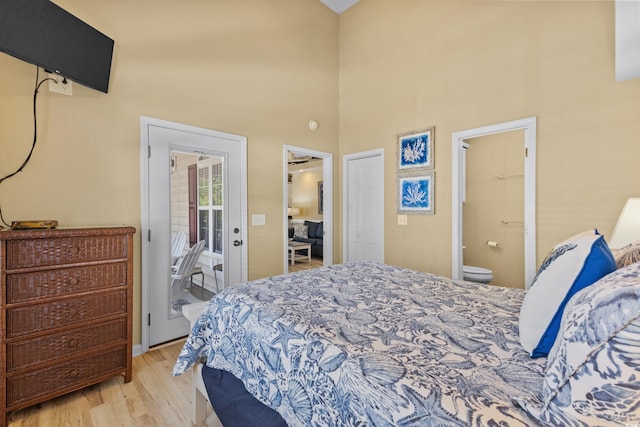 bedroom with ensuite bath, a closet, light hardwood / wood-style flooring, and a high ceiling