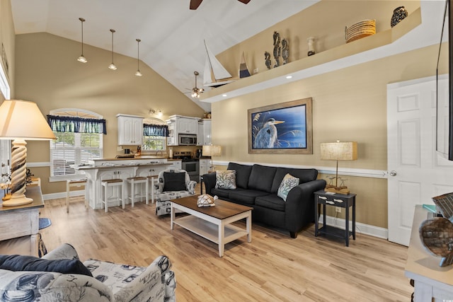 living room with light wood-type flooring, high vaulted ceiling, and ceiling fan