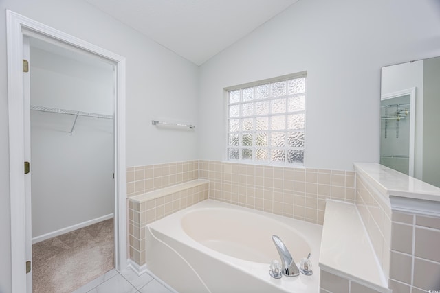 bathroom with tiled bath, tile patterned floors, and lofted ceiling