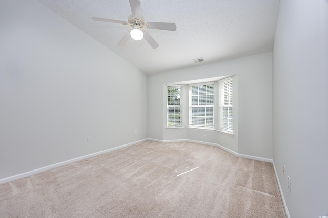 carpeted empty room with lofted ceiling, a textured ceiling, and ceiling fan