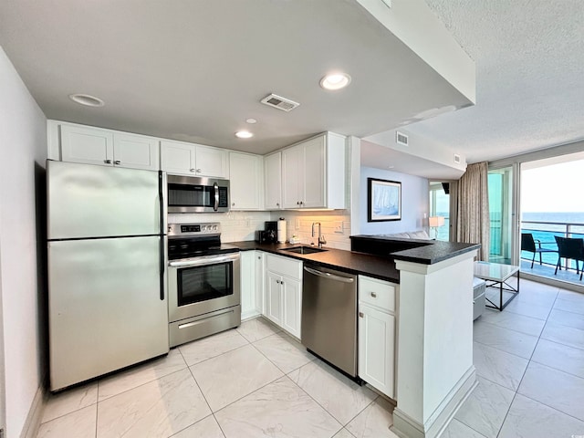 kitchen with white cabinetry, stainless steel appliances, tasteful backsplash, and kitchen peninsula