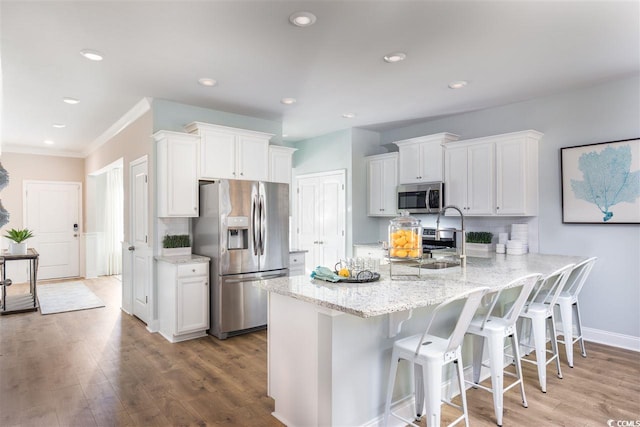 kitchen with light hardwood / wood-style floors, a breakfast bar, white cabinets, and stainless steel appliances