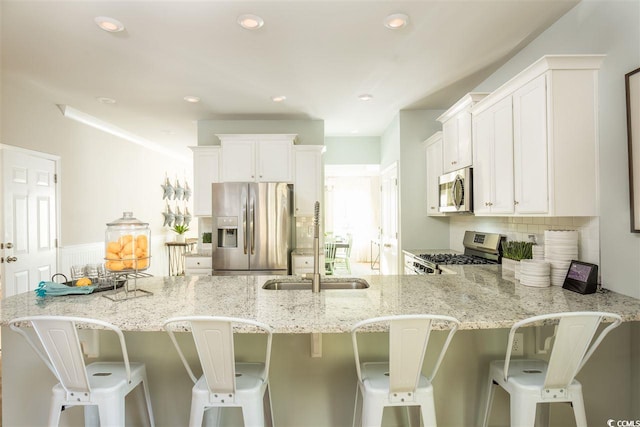 kitchen with backsplash, appliances with stainless steel finishes, a kitchen bar, and white cabinets