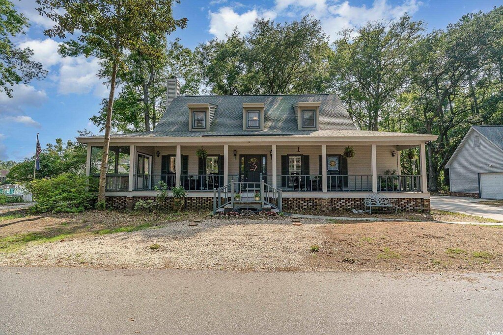 farmhouse inspired home featuring covered porch and a garage