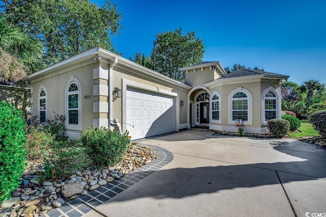 view of front of home featuring an attached garage, driveway, and stucco siding