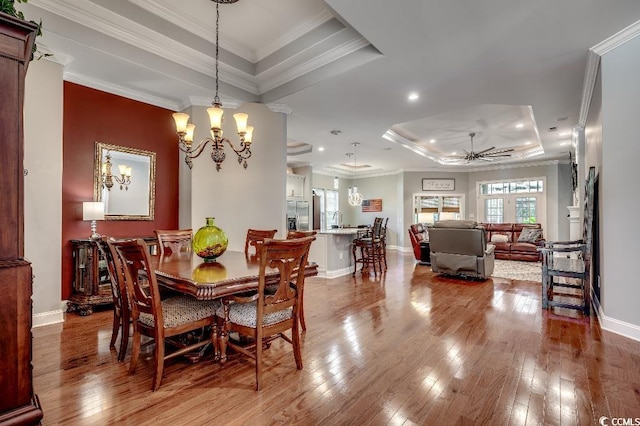 dining room with a raised ceiling, crown molding, and wood-type flooring