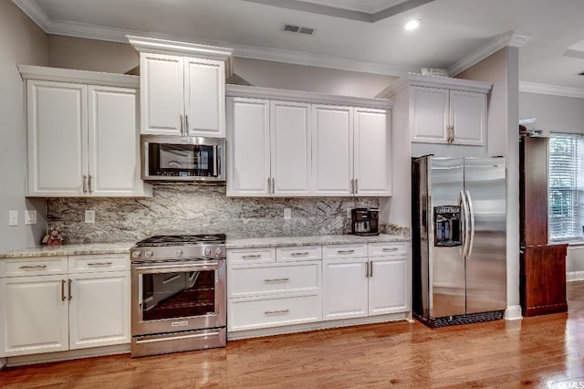 kitchen with white cabinets, visible vents, appliances with stainless steel finishes, and ornamental molding