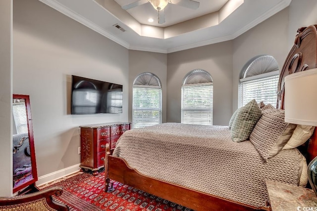 bedroom featuring visible vents, baseboards, crown molding, a raised ceiling, and ceiling fan