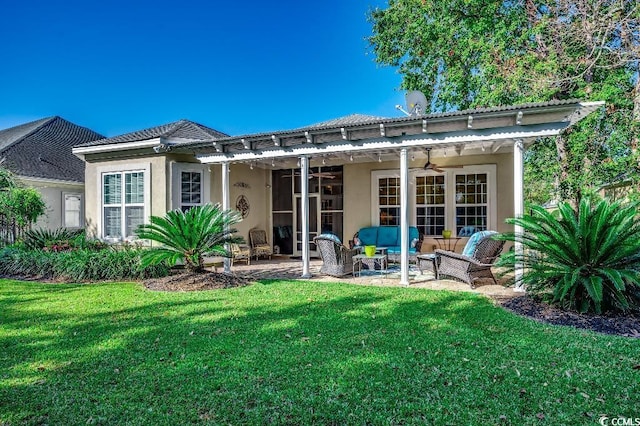 back of property featuring stucco siding, outdoor lounge area, a yard, a patio area, and a ceiling fan