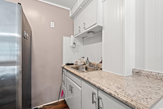 kitchen featuring white cabinetry, sink, light stone counters, stainless steel fridge, and dark hardwood / wood-style flooring