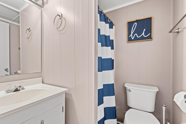 bathroom with toilet, vanity, and wooden walls