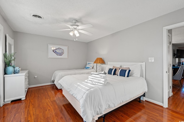 bedroom with wood-type flooring, ceiling fan, and a textured ceiling