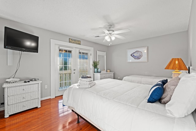 bedroom with access to outside, french doors, a textured ceiling, hardwood / wood-style flooring, and ceiling fan