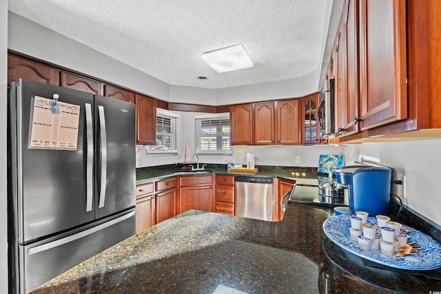 kitchen featuring dark stone countertops, sink, appliances with stainless steel finishes, and a textured ceiling