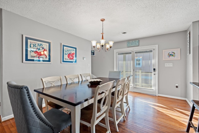 dining room featuring an inviting chandelier, hardwood / wood-style flooring, and a textured ceiling