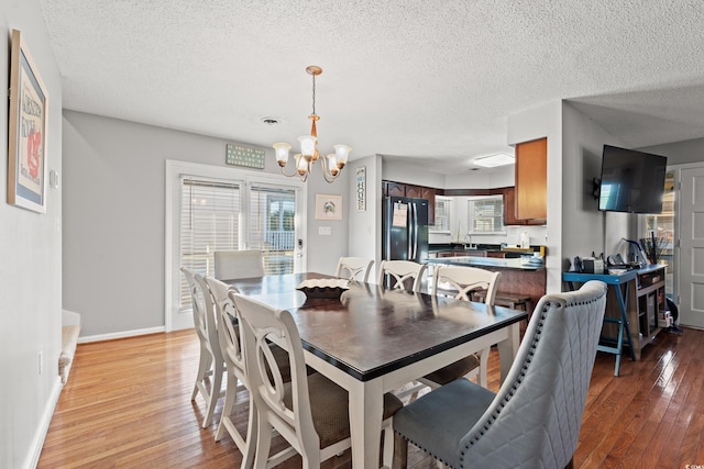 dining space featuring hardwood / wood-style floors, plenty of natural light, a textured ceiling, and a notable chandelier