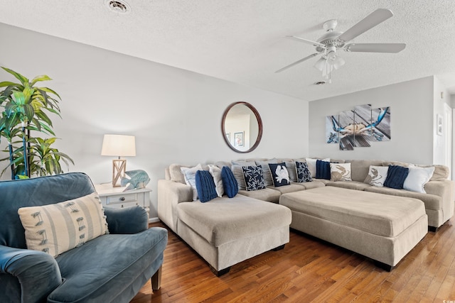 living room with dark wood-type flooring, a textured ceiling, and ceiling fan