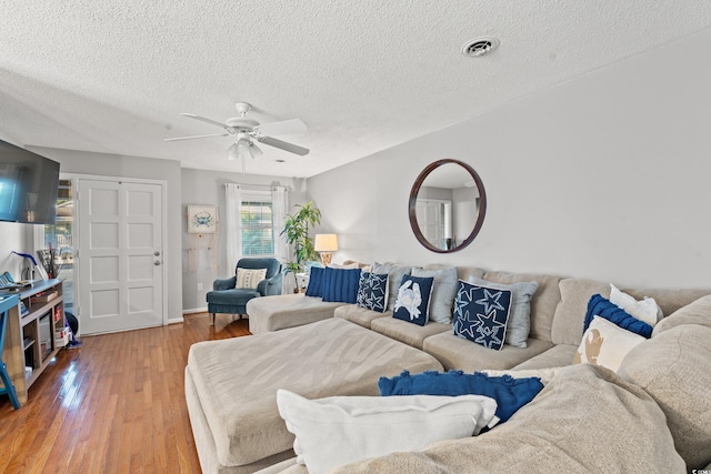 living room featuring a textured ceiling, hardwood / wood-style flooring, and ceiling fan