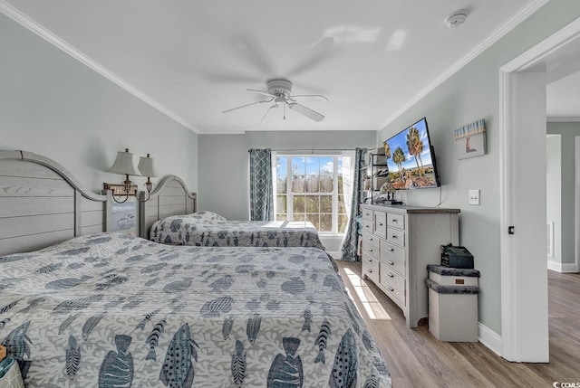 bedroom featuring wood finished floors, crown molding, baseboards, and a ceiling fan