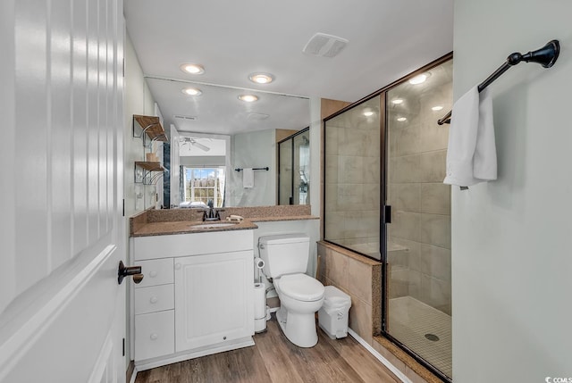 bathroom featuring a shower with door, wood-type flooring, toilet, ceiling fan, and vanity