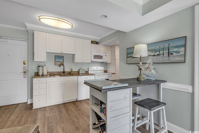 kitchen with white appliances, dark countertops, ornamental molding, a peninsula, and light wood-style flooring