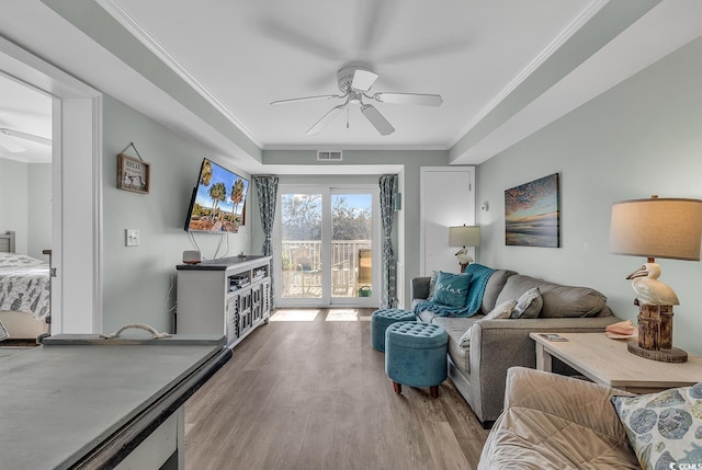 living room featuring a ceiling fan, crown molding, and wood finished floors