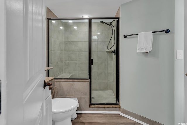 bathroom featuring toilet, an enclosed shower, and wood-type flooring