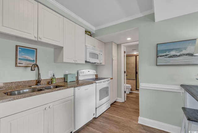 kitchen featuring white appliances, a sink, white cabinets, crown molding, and baseboards