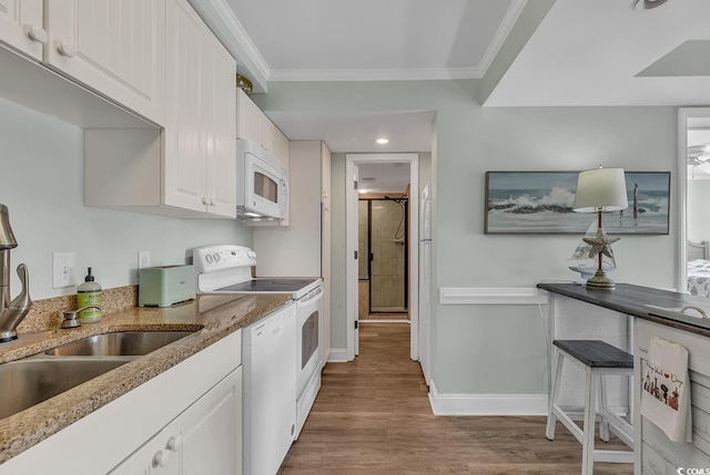kitchen with white appliances, crown molding, a sink, light stone countertops, and baseboards
