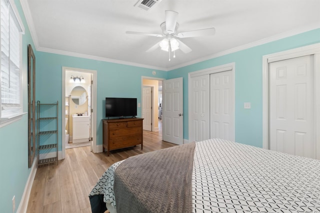 bedroom featuring ornamental molding, connected bathroom, light wood-type flooring, two closets, and ceiling fan