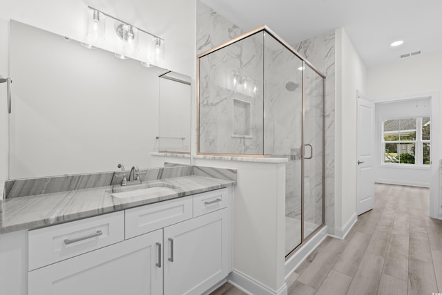 bathroom with hardwood / wood-style floors, an enclosed shower, and vanity