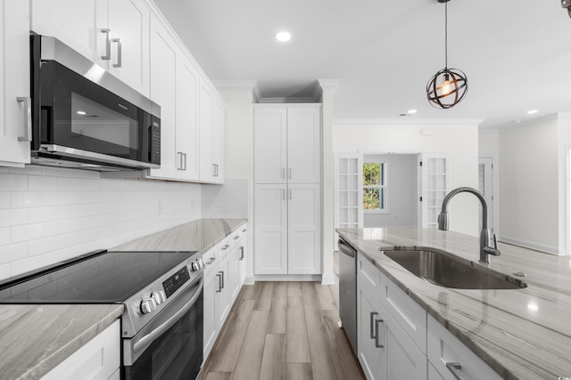 kitchen with light stone counters, decorative backsplash, crown molding, white cabinets, and appliances with stainless steel finishes