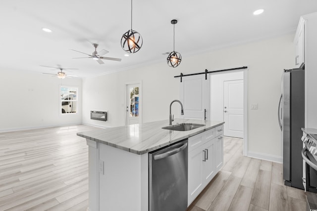 kitchen featuring a center island with sink, white cabinetry, a barn door, and appliances with stainless steel finishes