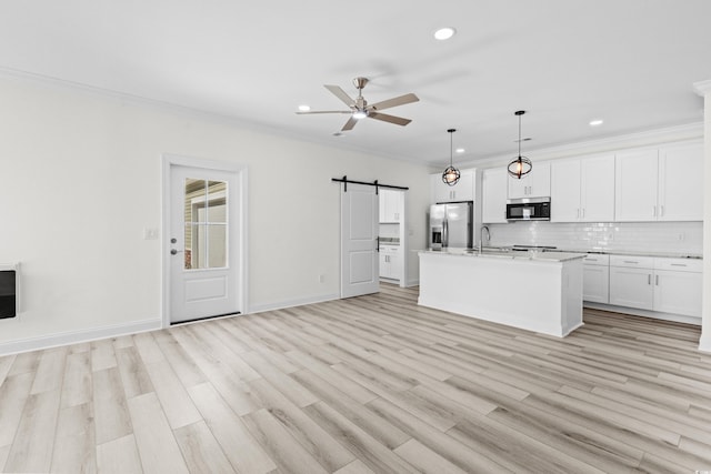 kitchen with decorative light fixtures, an island with sink, stainless steel refrigerator with ice dispenser, a barn door, and white cabinetry