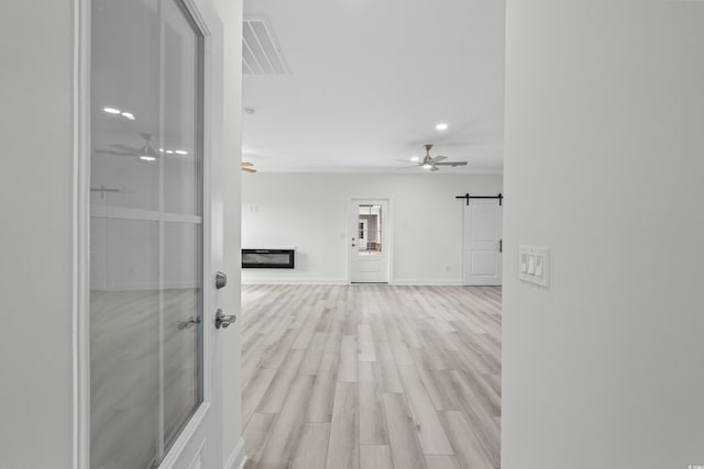 hallway featuring a barn door and light hardwood / wood-style floors