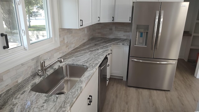 kitchen with light stone counters, white cabinets, appliances with stainless steel finishes, and a sink