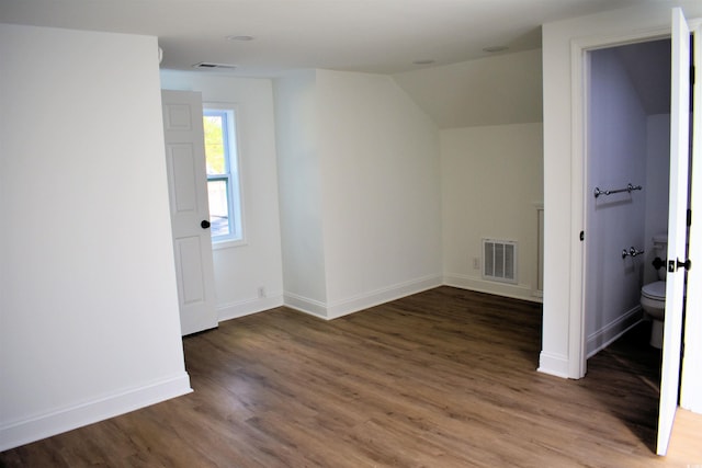 spare room featuring visible vents, lofted ceiling, baseboards, and wood finished floors