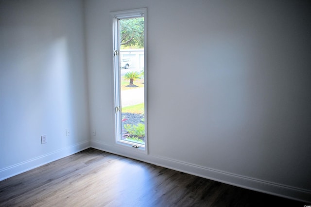 spare room with a healthy amount of sunlight, baseboards, and dark wood-style flooring