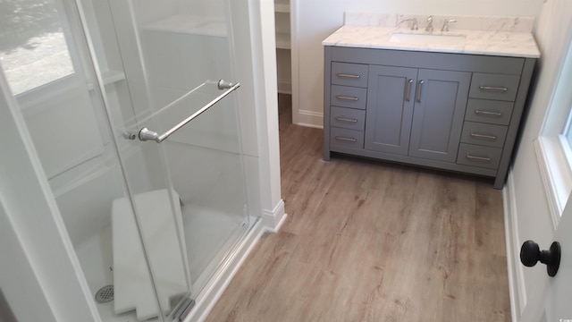 bathroom featuring vanity, wood finished floors, a stall shower, and baseboards