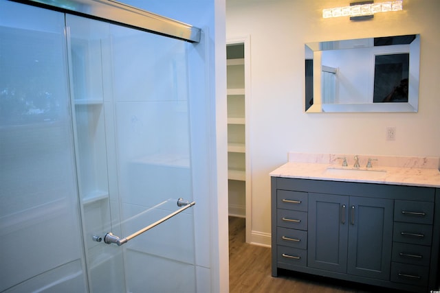 full bath featuring a spacious closet, walk in shower, wood finished floors, and vanity