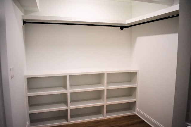 walk in closet with dark wood-style floors