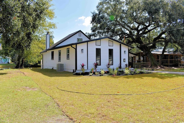 view of front of property with a front yard, central AC unit, and a chimney