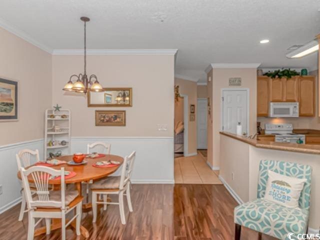 dining area with crown molding, hardwood / wood-style flooring, and a chandelier