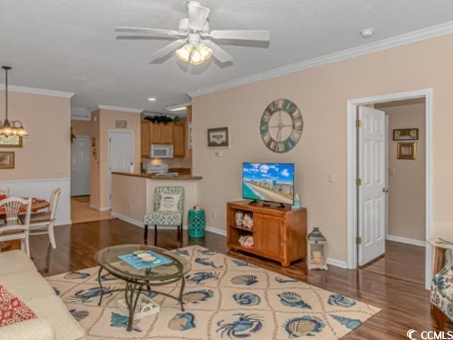 living room with ornamental molding, wood-type flooring, and ceiling fan with notable chandelier