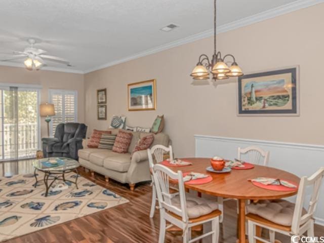 dining room featuring hardwood / wood-style flooring, ornamental molding, and ceiling fan with notable chandelier