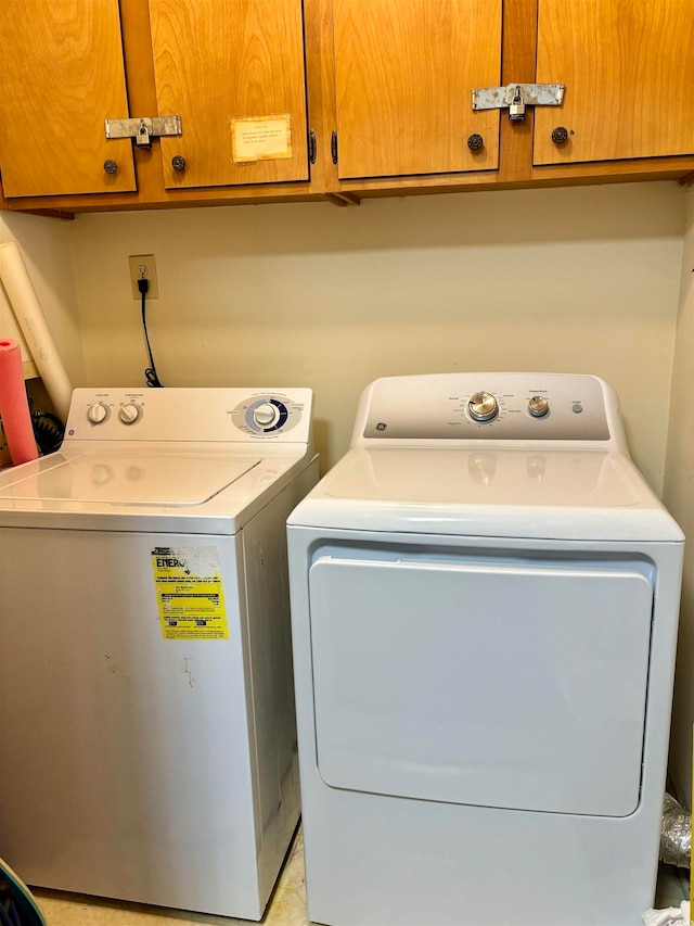 clothes washing area featuring washing machine and dryer and cabinets