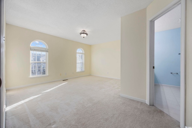 spare room with a textured ceiling and light colored carpet