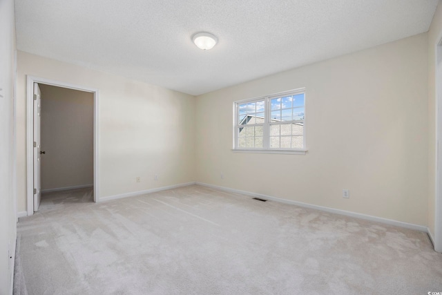 empty room featuring a textured ceiling and light colored carpet