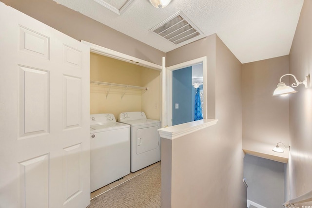 washroom featuring light carpet, a textured ceiling, and washer and clothes dryer