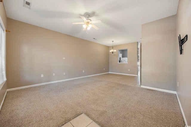 empty room featuring light carpet, a textured ceiling, and ceiling fan with notable chandelier